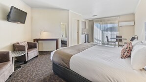 A hotel room with a large bed, two armchairs, a small table, a desk, a TV, and a window with curtains. - Comfort Inn Clubarham (Barham)
