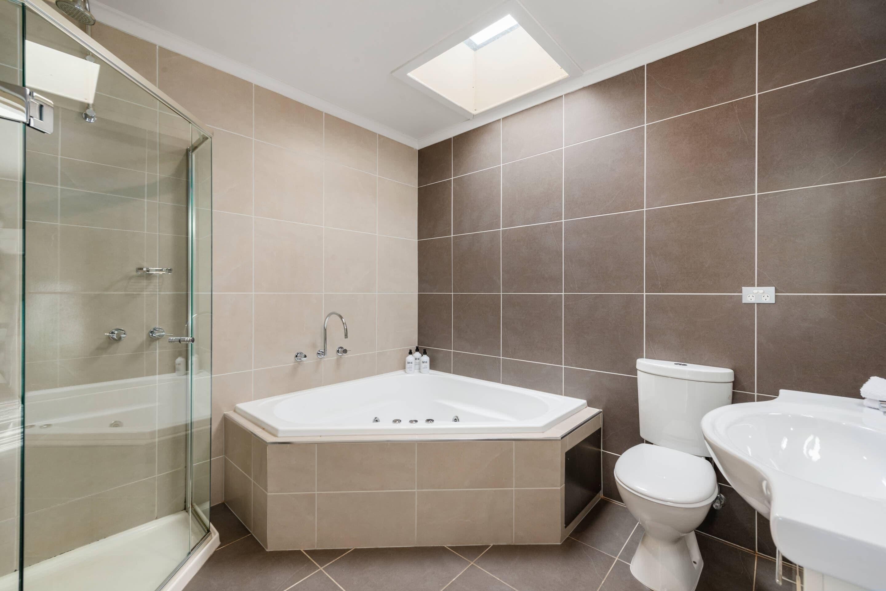 A modern bathroom with a glass-enclosed shower, a freestanding bathtub, a toilet, and a sink.