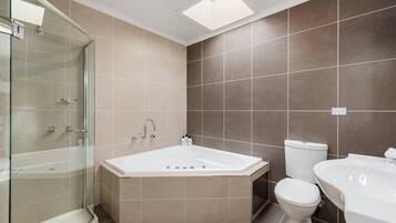 A modern bathroom with a glass-enclosed shower, a freestanding bathtub, a toilet, and a sink.