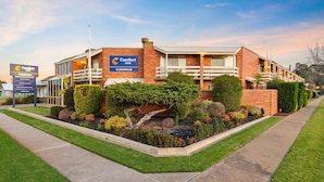 A Comfort Inn Clubham building with a brick facade, multiple balconies, and a landscaped garden area. - Comfort Inn Clubarham (Barham)