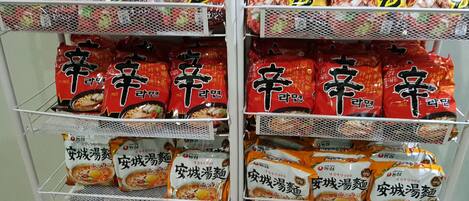 A shelf stocked with various packaged food items, including instant noodles and other snacks.