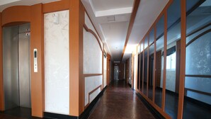 A long, narrow hallway with a marble floor, wooden paneling, and large windows on one side. - Bali Motel (Gongju)
