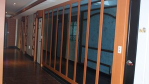 A hallway with a wooden door on the right, a glass door on the left, and a patterned wall. - Bali Motel (Gongju)