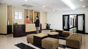 Un hall d’hôtel moderne avec un comptoir d’accueil, un espace salon et un grand miroir.