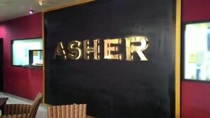 Un mur sur lequel est inscrit le mot « ASHER » en grandes lettres dorées.