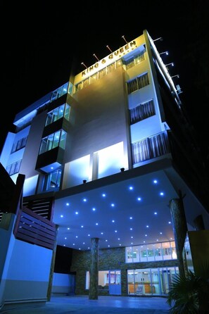 A multi-story hotel with a prominent sign reading "KING & QUEEN." The building features balconies, large windows, and a covered entrance area with blue lighting. - King & Queen Hotel (Monywa)