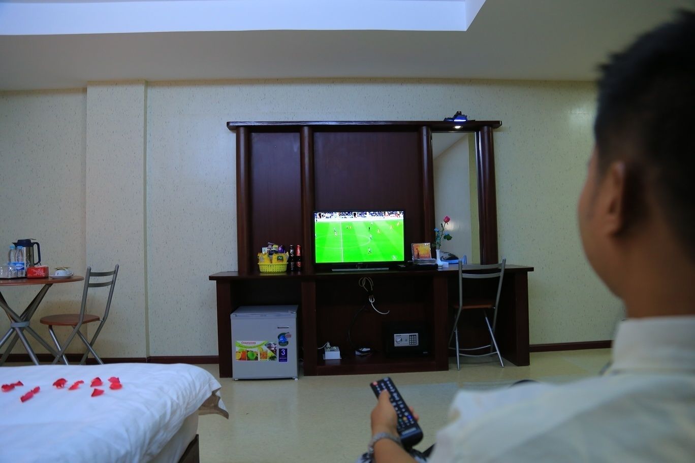 Ein Hotelzimmer mit einem Bett, einem Schreibtisch mit Fernseher und einem Sessel.