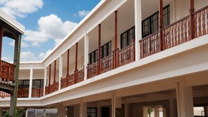 Un edificio de varios niveles con paredes exteriores blancas, múltiples balcones con barandillas de madera y ventanas grandes.