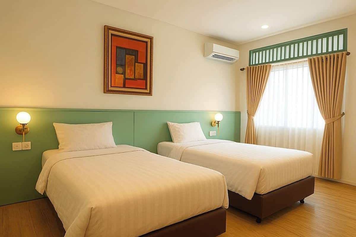 A hotel room with two beds, a green headboard, a painting, an air conditioning unit, and a window with curtains.