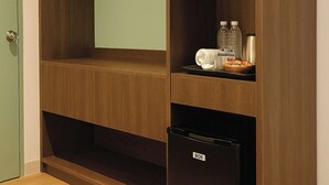 Un armario de madera con espejo, barra para colgar ropa y un refrigerador pequeño.