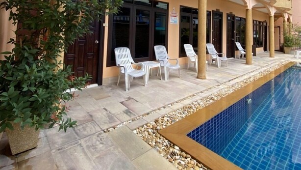 Un hotel con piscina, mobiliario exterior y un balcón de varios niveles.