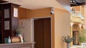 Zona de recepción con mobiliario de mimbre, un mostrador de recepción y una piscina al fondo.