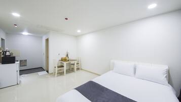 A hotel room with a bed, a desk, and a chair.