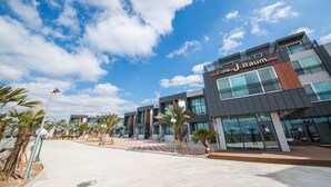 Un hotel moderno con fachada de vidrio, zona de estar al aire libre y palmeras.