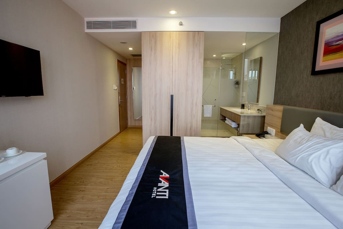 Ein Hotelzimmer mit einem Bett, einem Nachttisch, einem Spiegel und einem an der Wand montierten Fernseher.
