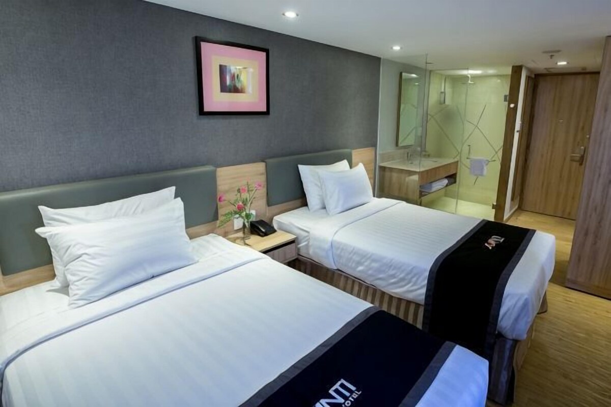 Een hotelkamer met twee bedden, een nachtkastje, een spiegel en een houten deur.
