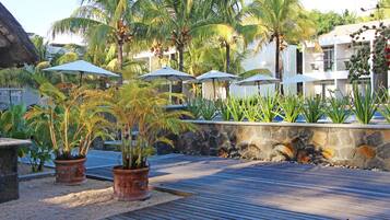 Een tropisch resort met palmbomen, planten in potten en parasols.