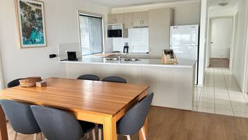 A modern kitchen with a wooden dining table and chairs, a microwave, and a refrigerator.