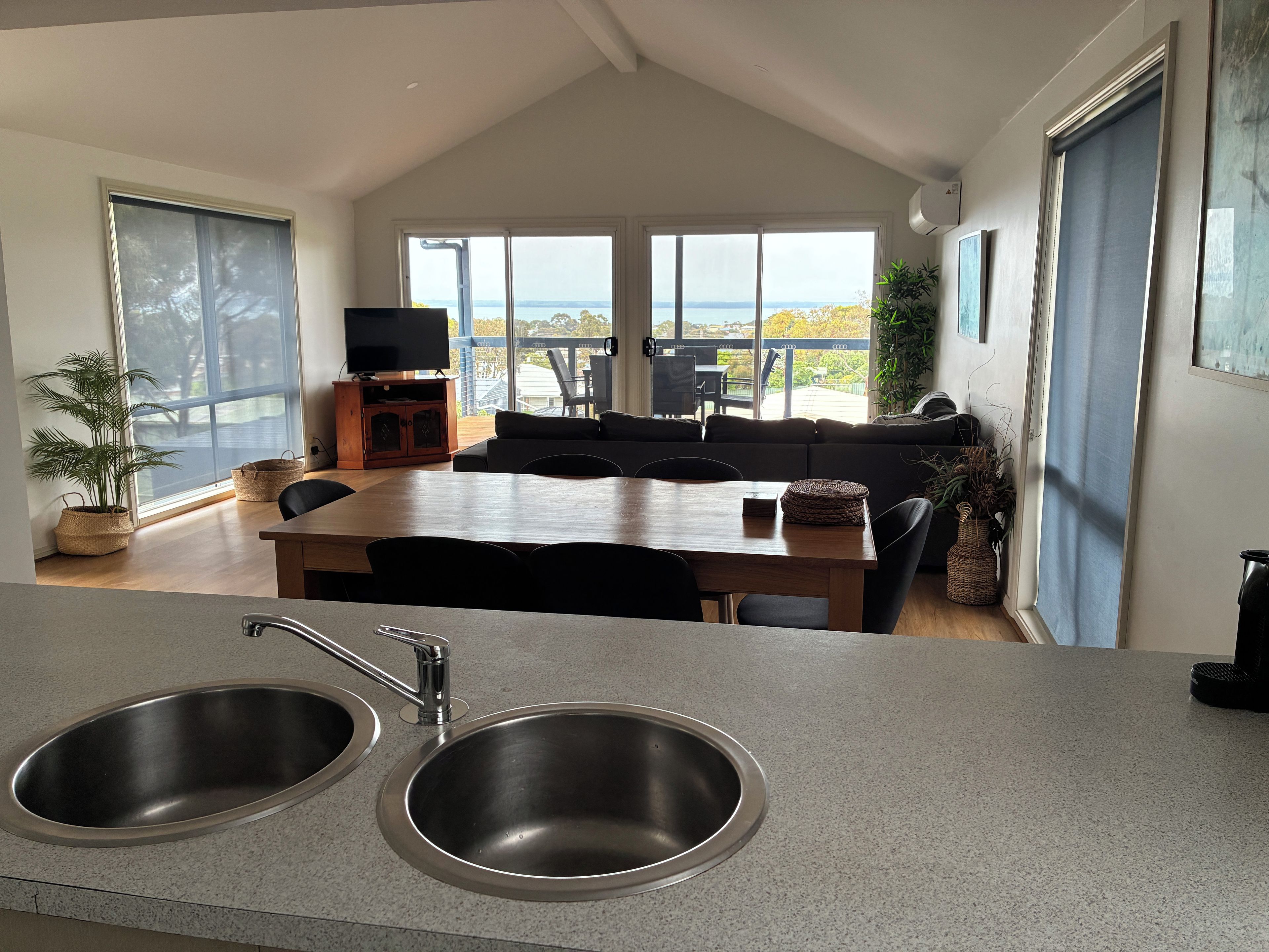 A modern kitchen with a dining area, large windows, and a view of the outdoors.