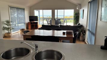 A modern kitchen with a dining area, large windows, and a view of the outdoors.