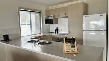 A modern kitchen with a central island, stainless steel appliances, and a view of the outdoors.
