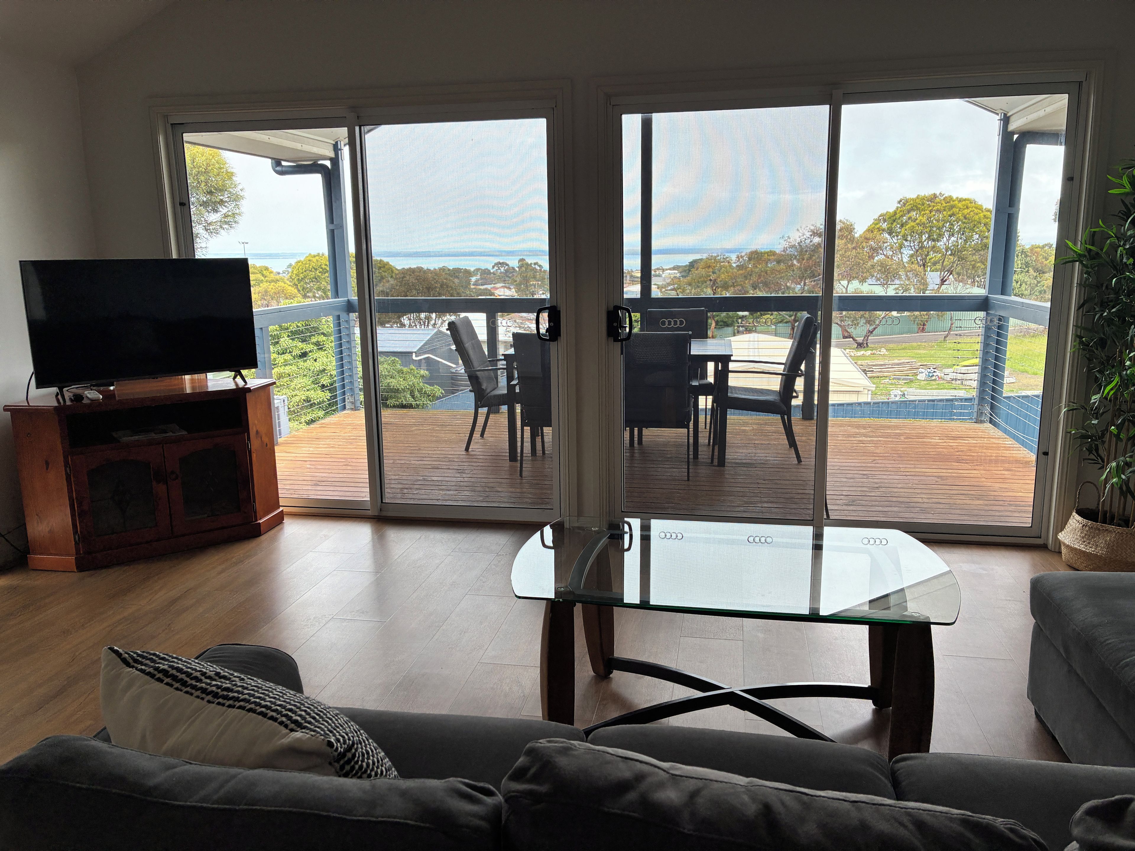A living room with a television, a glass-top coffee table, and a sofa.