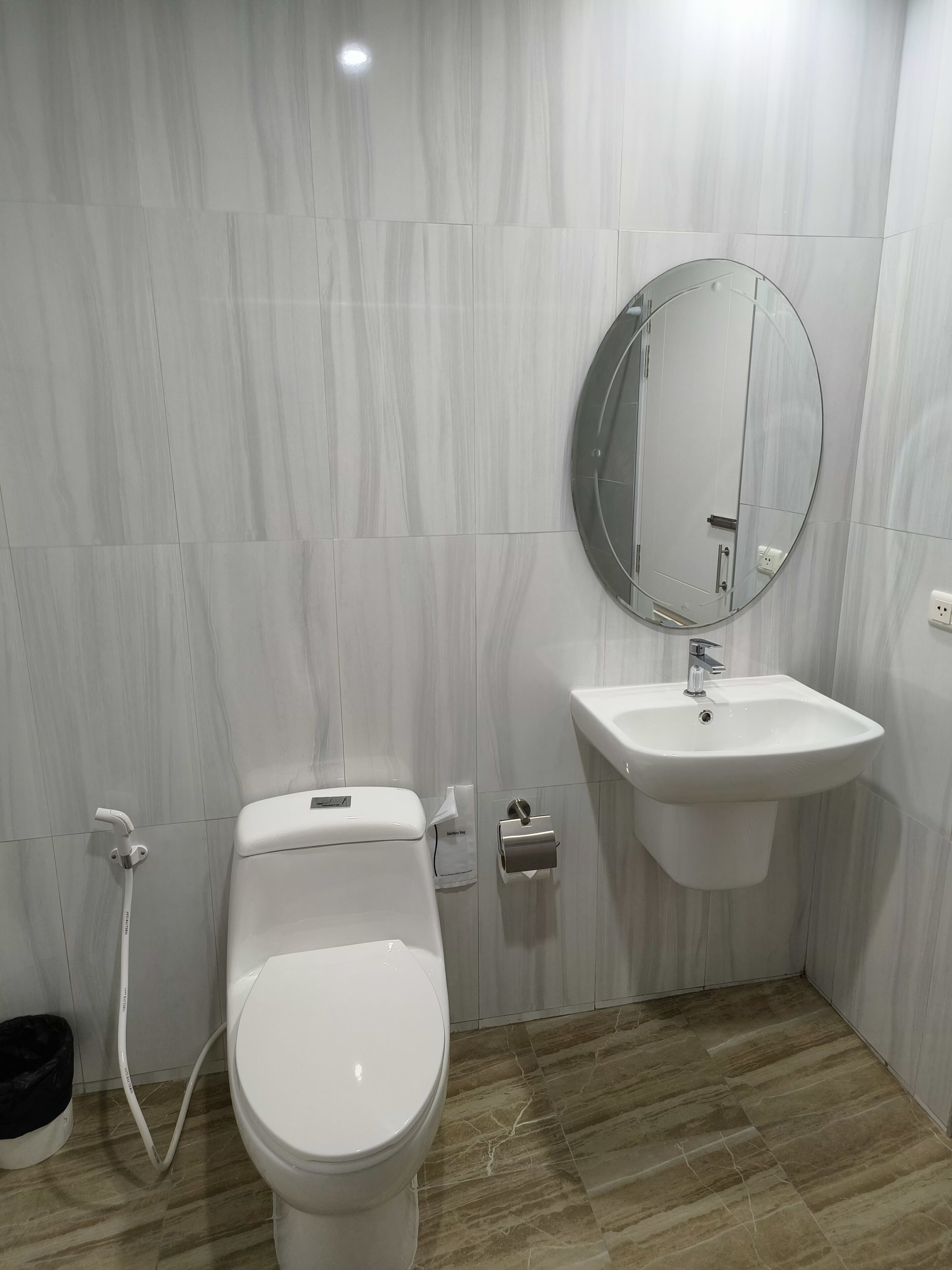 A bathroom with a toilet, sink, and mirror.