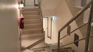 A staircase with metal railings and a fire extinguisher on the wall. - Aonang Goodwill Hotel (Krabi)
