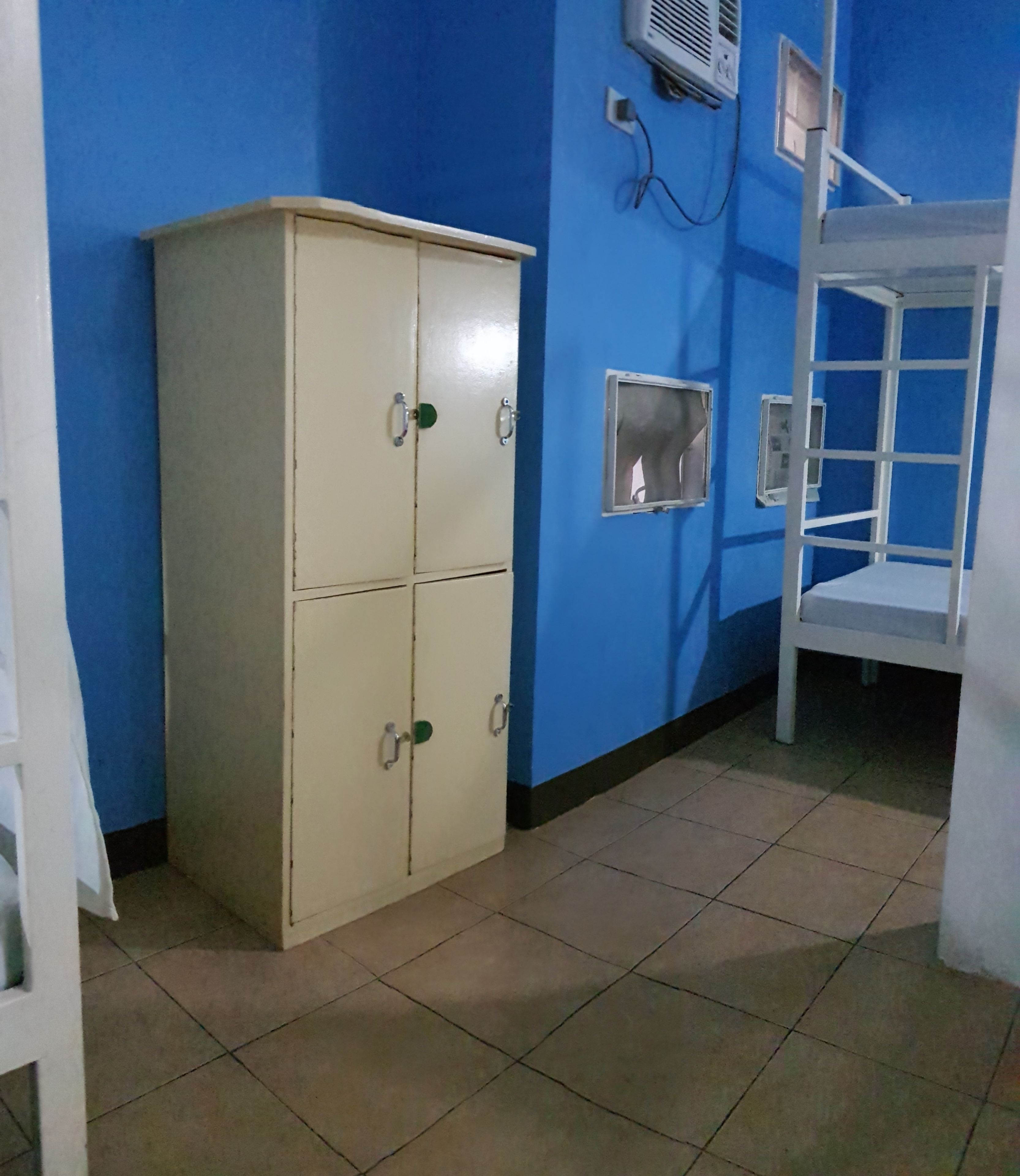 Una habitación con un armario color beige, una litera y una pared azul.