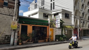 A hostel with a green awning, outdoor seating, and potted plants. - Crossroads Hostel Manila (Mandaluyong)