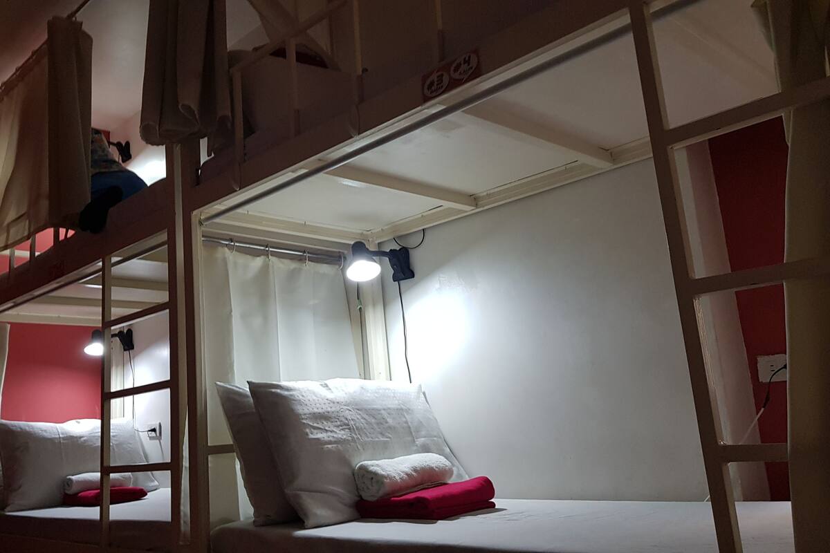 A bunk bed room with a red wall, a white ceiling, and a single light fixture.