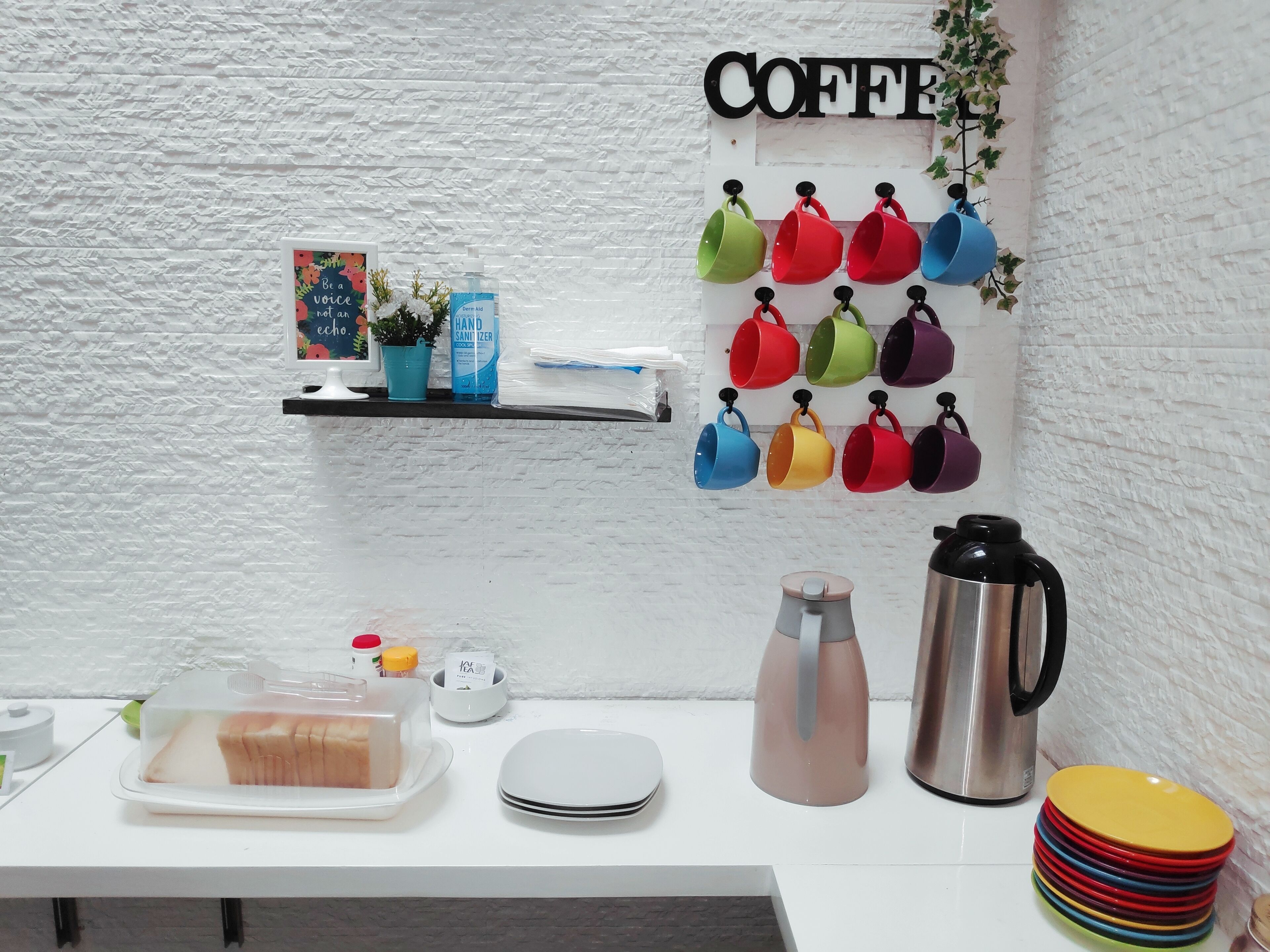 Una encimera de cocina con rincón para café, que incluye tazas, una tetera y un ceñidor.