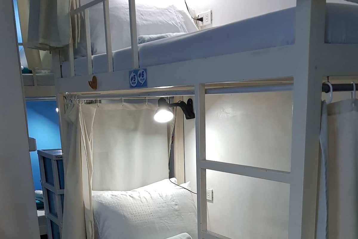 A bunk bed with a white mattress, a blue blanket, and a white pillow.