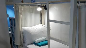 Uma cama beliche com colchão branco, cobertor azul e travesseiro branco.