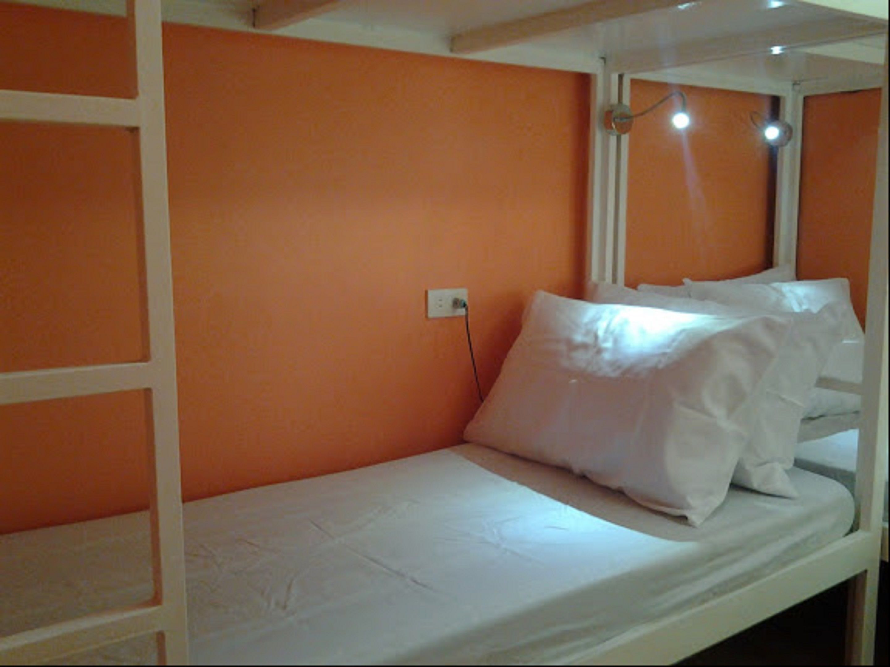 A bunk bed with white bedding in a room with orange walls.