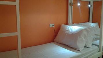 A bunk bed with white bedding in a room with orange walls.