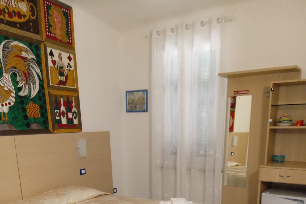A hotel room with a large bed, a desk, a small refrigerator, and a cabinet.