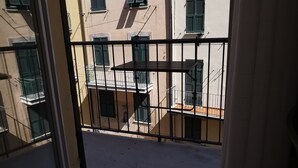 A balcony with metal railings and a view of adjacent buildings with multiple windows and balconies. - Il BoMa Affittacamere (Riomaggiore)