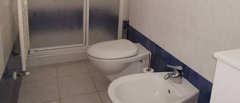 Un bagno con un WC, un bidet e una cabina doccia.