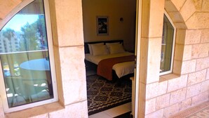 A hotel room with a bed, a window, and a view of the outside. - Alhambra Palace Hotel Suites (Ramallah)