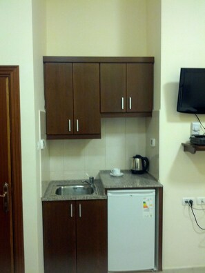 A compact kitchen with a built-in dishwasher, a sink, and a small countertop. - Alhambra Palace Hotel Suites - Ramallah (Ramallah)