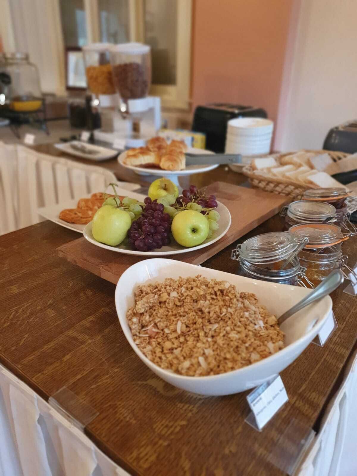 A breakfast buffet with various food items including fruits, pastries, and granola.
