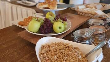 A breakfast buffet with various food items including fruits, pastries, and granola.