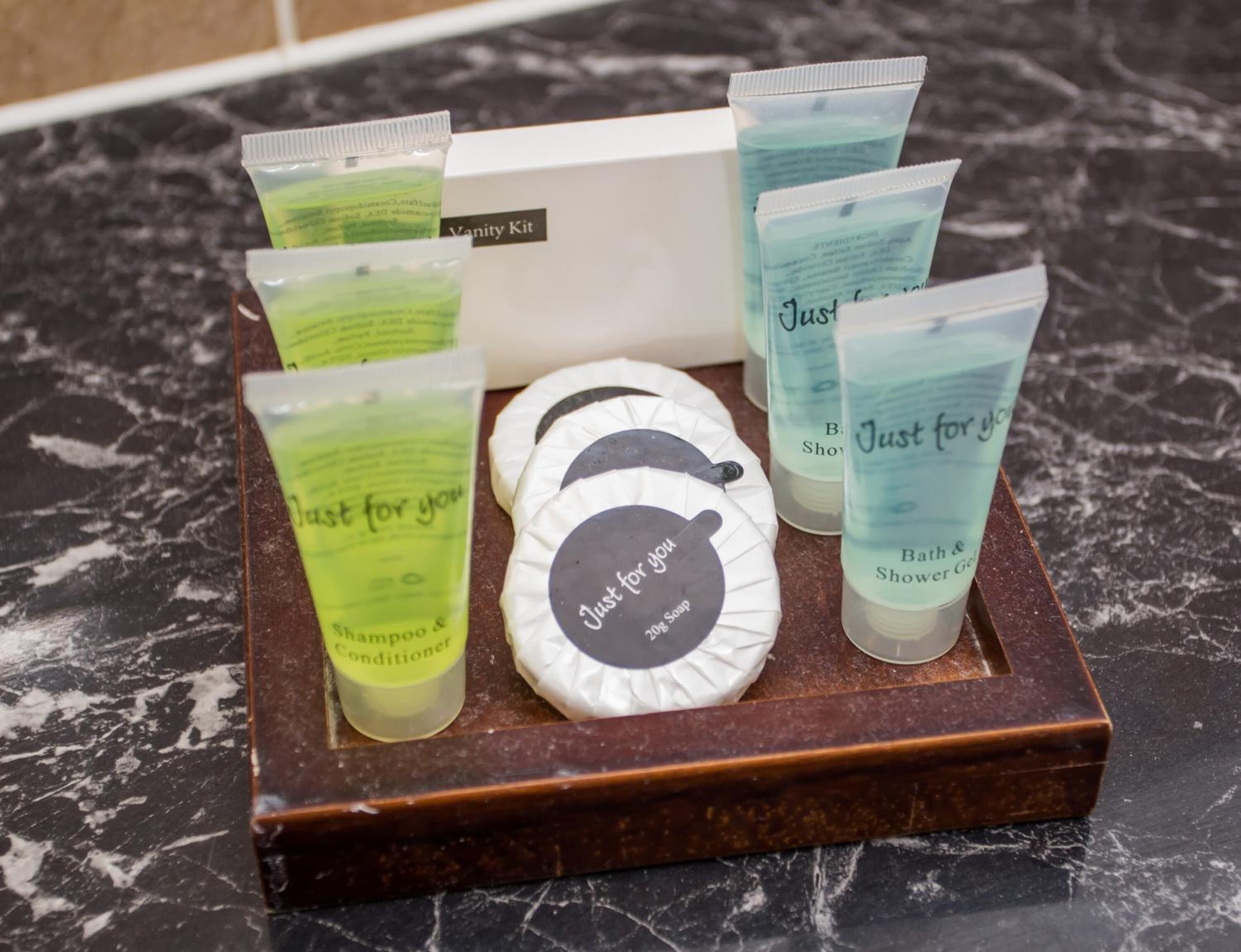 A vanity kit with shampoo, conditioner, and bath soap on a marble countertop.