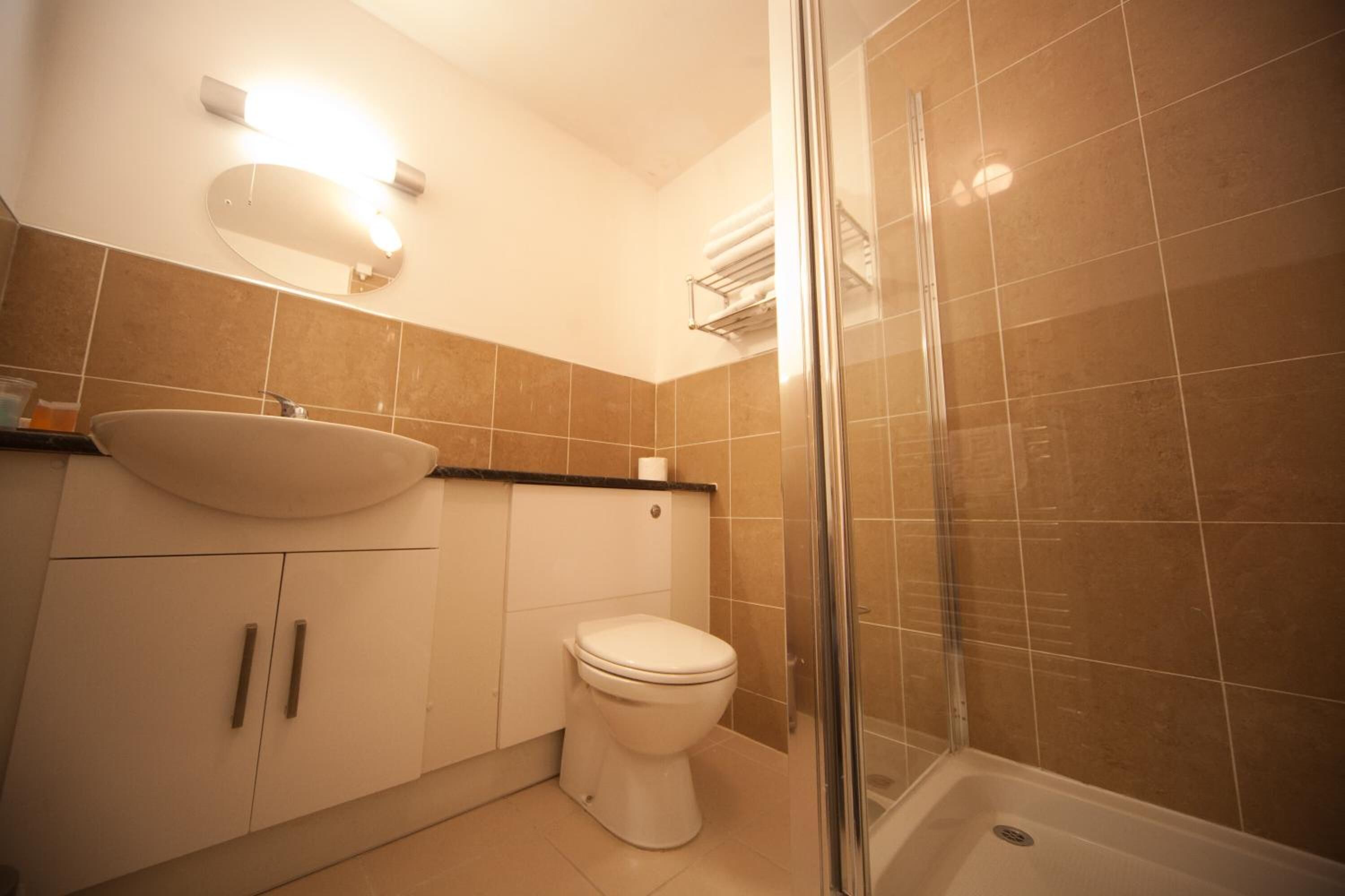 Une salle de bain équipée d’un lavabo, de toilettes et d’une douche à parois en verre.