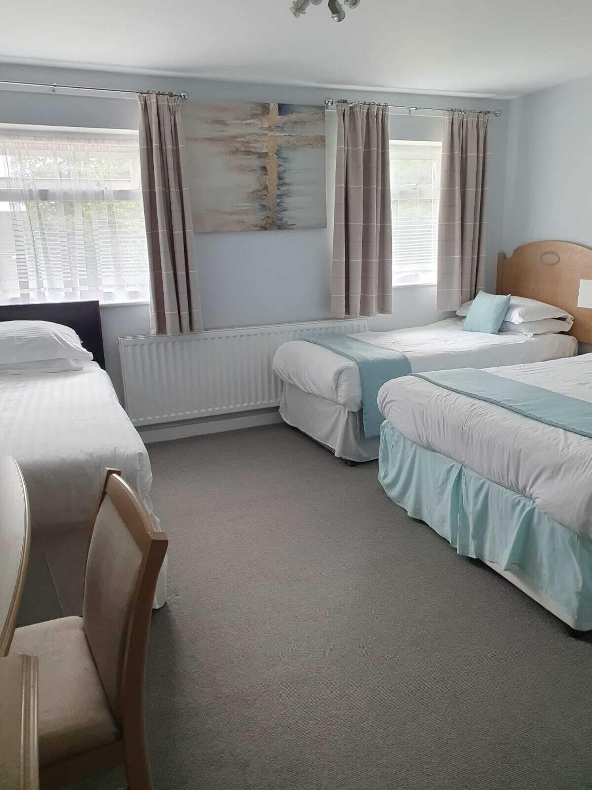 A hotel room with two beds, a radiator, and a window with curtains.