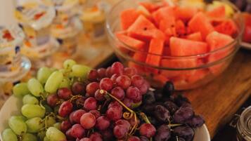 A table with various food items including bowls of grapes, watermelon, and other fruits.