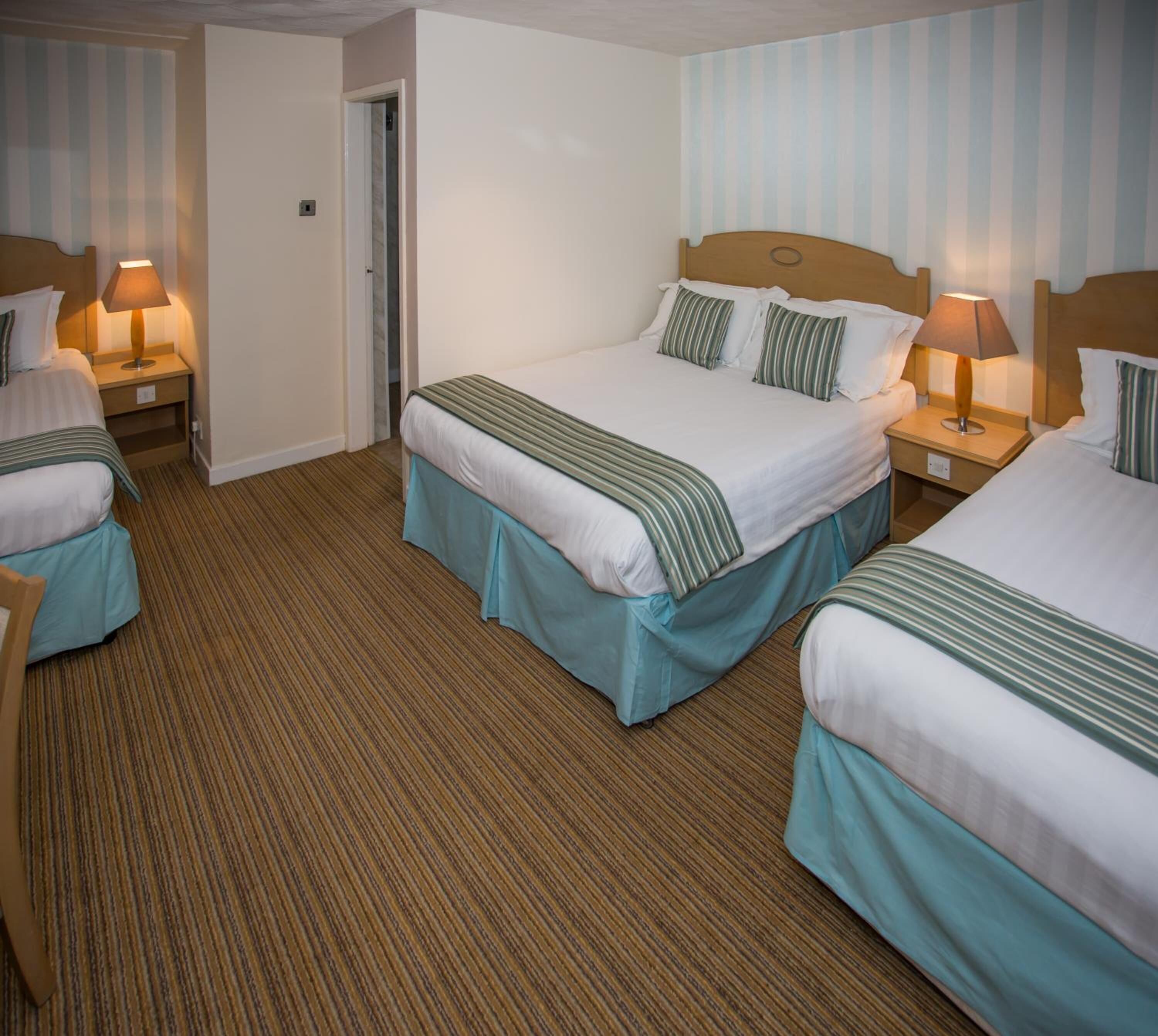A hotel room with two beds, striped bedding, and a striped carpet.