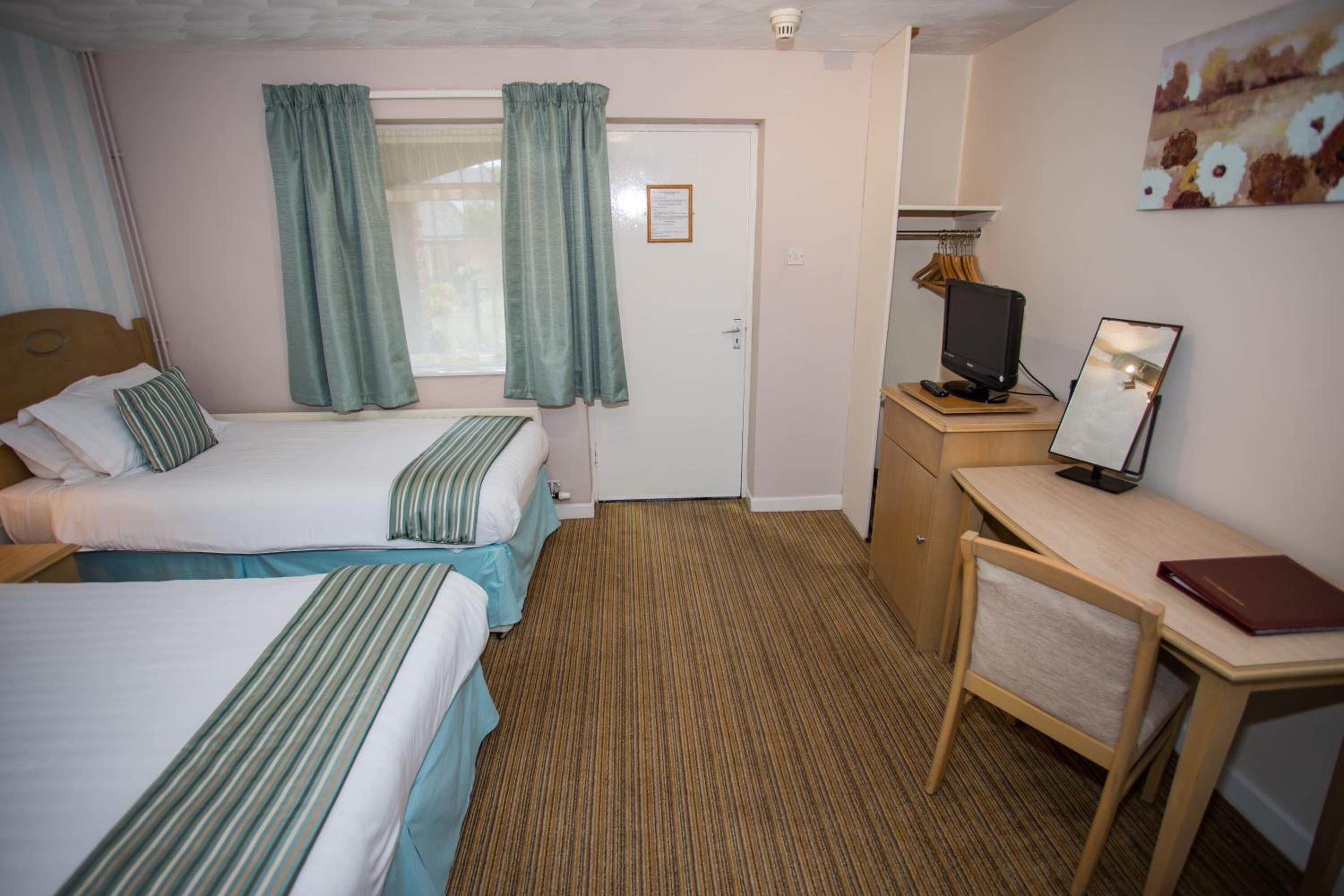 A hotel room with two beds, a desk with a computer, and a TV.