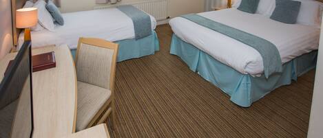 A hotel room with two beds, a desk, and a chair.